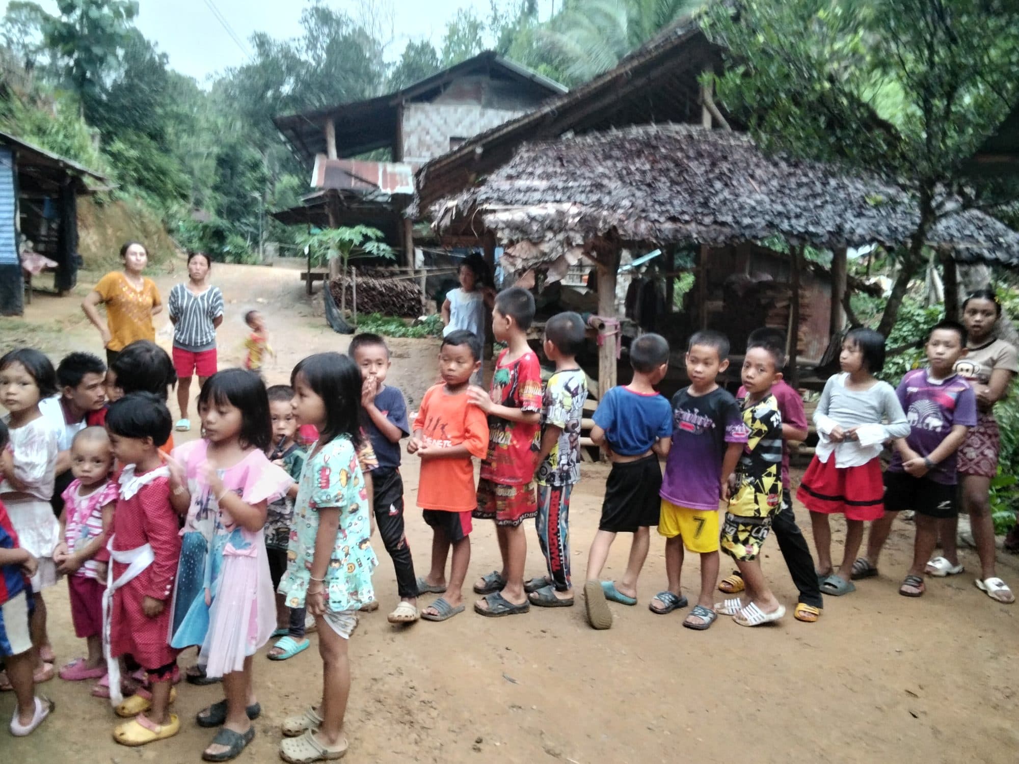Children of the village gathered together on open ground by their homes.